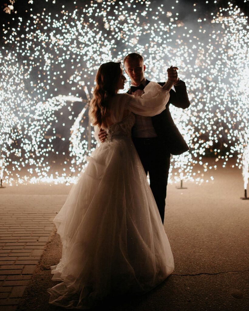 A couple shares a romantic dance at night surrounded by stunning fireworks for their wedding celebration.