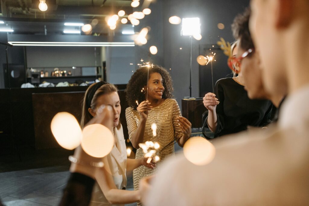 A group of diverse adults celebrating indoors with sparklers, creating a festive atmosphere.